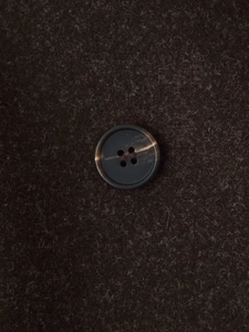 Macro shot of dark brown wool fabric texture with a classic four-hole resin button detail