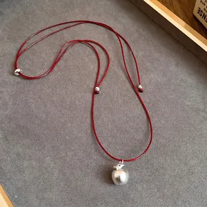 Minimalist red leather cord necklace with a matte silver apple pendant and silver beads
