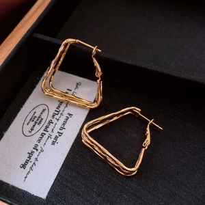 Detailed view of gold-plated geometric triangle earrings on a luxury jewelry box