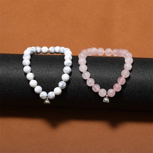 Close-up of white turquoise and rose quartz beaded bracelets with metal bells on a display
