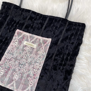 Gros plan du sac cabas en velours noir avec broderie en dentelle et étiquette Suzakka