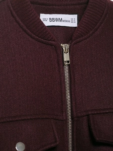 Detailed close-up of wine red wool jacket collar with premium metal zipper and pocket texture