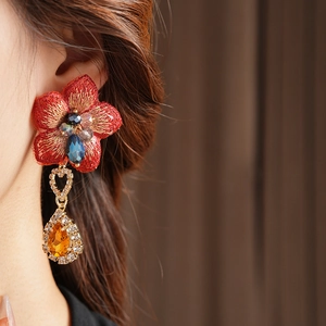 Détail d'une boucle d'oreille fleur en tissu vintage avec cristal bleu et goutte d'ambre