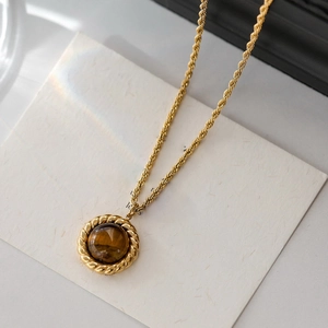 Close-up of golden rope chain necklace with a round tiger eye stone pendant
