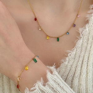 Gold plated necklace and bracelet set with colorful rainbow cubic zirconia on white sweater