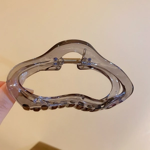 Détail de la pince à cheveux ondulée en acrylique gris foncé avec ressort métallique