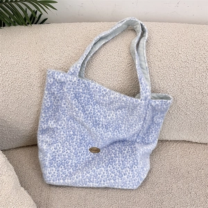 Détail du sac cabas en peluche léopard bleu clair avec logo métallique sur tissu