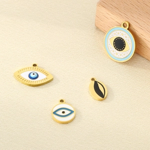 Detailed view of four assorted gold-plated enamel evil eye pendants on textured fabric
