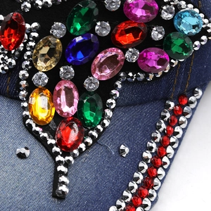 Detailed view of colorful large rhinestones and crystal beads on dark blue denim fabric