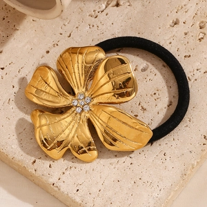 Elegant 18K gold plated flower hair tie with rhinestones on a textured stone base