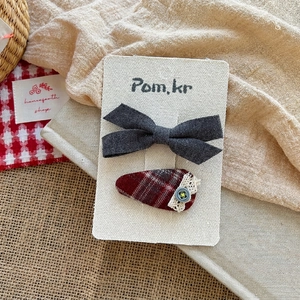 Detail of handmade bow hair clips in gray cotton and red plaid with lace and button