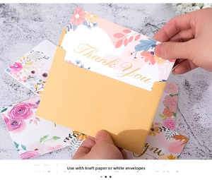 Detail of hand placing a floral 'Thank You' card into a kraft paper envelope
