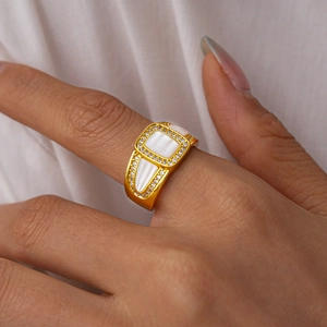 Détail de la bague dorée avec incrustation de nacre et zircons portée au doigt
