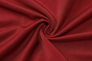Macro shot of dark red ribbed knit fabric texture showing elasticity and soft drape