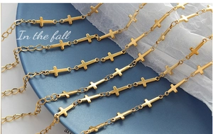 Macro detail of 18K gold-plated stainless steel cross chain links on a dark blue plate