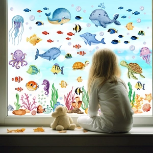 Girl looking through window decorated with cartoon sea animal stickers like whales and dolphins