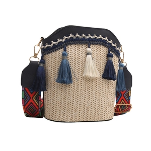 Detail of bohemian straw bucket bag featuring tassels and a colorful geometric strap