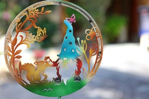 Detail of colorful solar garden stake with hollow metal gnome and squirrel silhouettes