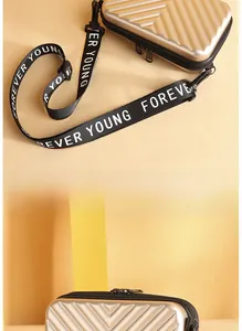 Detail of champagne gold mini suitcase crossbody bag with V-shaped texture and strap