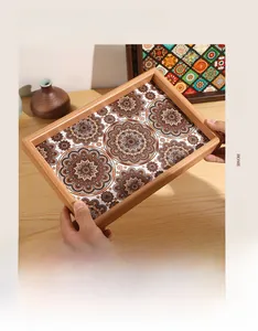 Close-up of rectangular wooden tray with brown mandala patterns held by hand