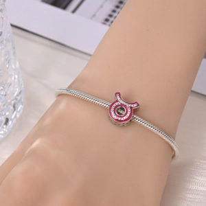 Close-up of pink enamel Taurus zodiac charm on silver snake chain bracelet with rhinestones
