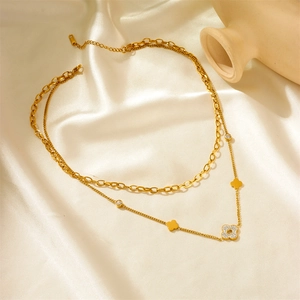Gold double-layered necklace with zircon clover pendant on elegant beige silk