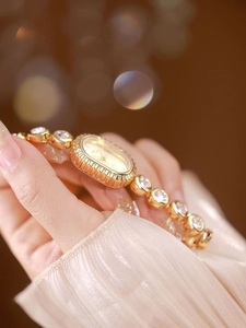 Close-up of elegant gold oval watch with diamond-set bracelet on woman wrist