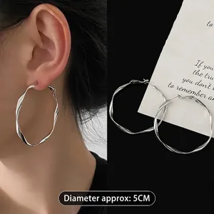 Macro detail of 5cm silver geometric twist hoop earrings shown on model and flat lay