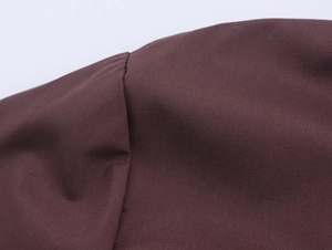 Close-up of chestnut brown woven fabric texture and precision stitching on the garment