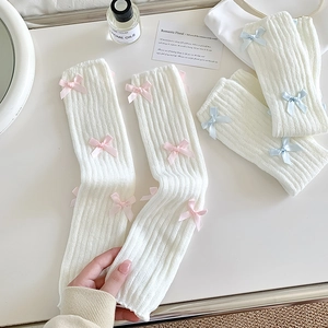 Texture de maille des jambières blanches avec de petits nœuds en satin rose et bleu