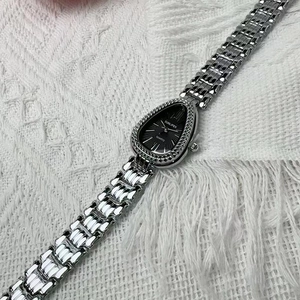 Detail of silver snake-pattern bezel and drop-shaped black dial on women's quartz watch