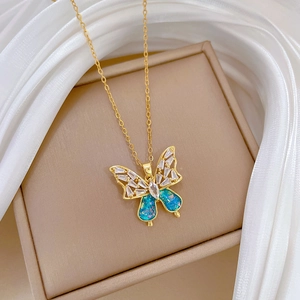 Macro shot of gold-plated butterfly necklace with blue glitter and crystals on silk