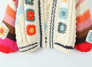 Détail d'un cardigan au crochet fait main avec motifs floraux et manches rayées