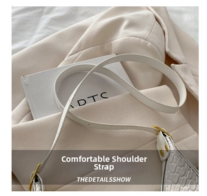 Detail view of the white crocodile texture shoulder bag with golden metal buckle and strap
