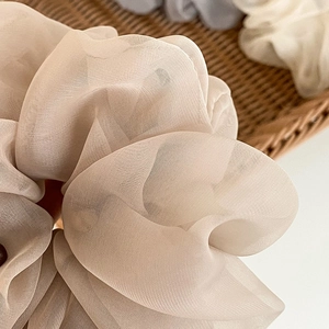 Close-up of elegant beige organza scrunchie showing delicate sheer fabric texture