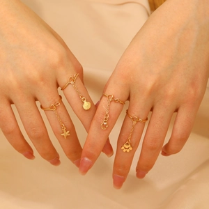 Set of 4 gold rings with starfish, shell, and hamsa hand pendants on hands
