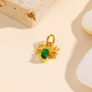 Detailed view of a gold spider pendant with an oval green gem on a natural stone base