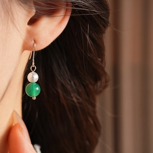 Dettaglio di orecchini vintage in argento con perla bianca e perla di agata verde