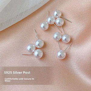 Macro detail of S925 sterling silver needles and round white pearls on pink satin