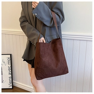 Borsa tote marrone in pelle scamosciata indossata da una modella per un look elegante e sobrio
