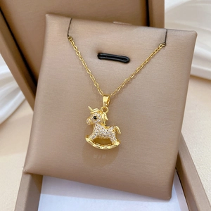 Macro shot of gold plated titanium necklace with crystal-pave horse pendant in gift box