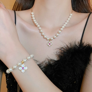 Elegant vintage pearl necklace and bracelet set with ruby-colored zircon pendants on model