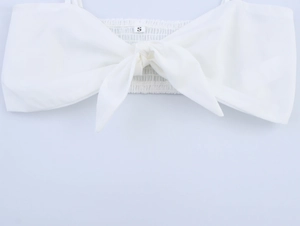 Detail eines weißen Crop-Tops mit vorderer Schleife und elastischem gesmoktem Rücken