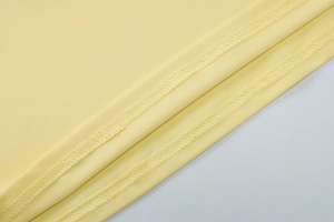 Dettaglio macro del tessuto a maglia giallo con cuciture di qualità e finitura fine