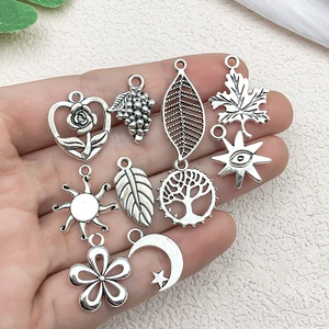 Vintage silver alloy charms set with sun, moon, and heart designs held in palm