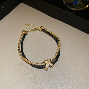 Gros plan du pendentif croisé en zircon plaqué or avec bracelet tressé à double couche