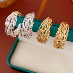 Detail of twisted gold and silver hoop earrings inside a green velvet jewelry display box
