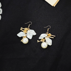 Detail of French vintage earrings with white petals, pearl and gold key tassel charms