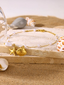 Detail of a gold beach jewelry set featuring shell, starfish charms and white pearls