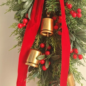 Christmas door hanging with golden bells, red velvet ribbons and green pine needles